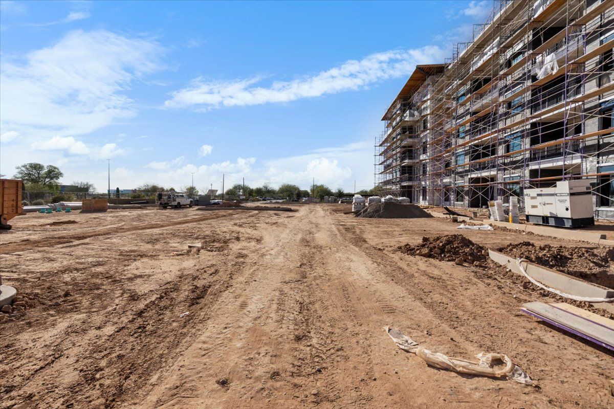 A large building is being built on a dirt road.