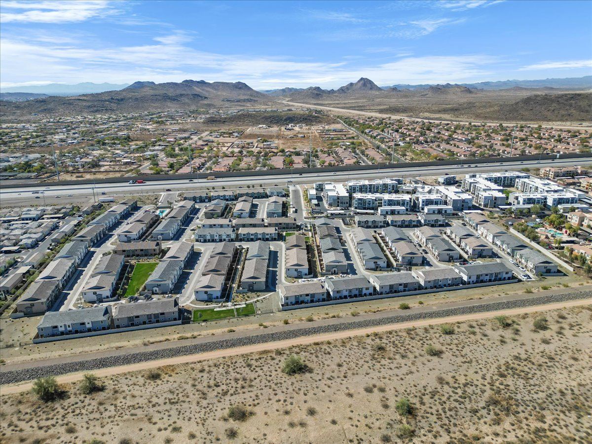 An aerial view of a residential area in the desert with mountains in the background.