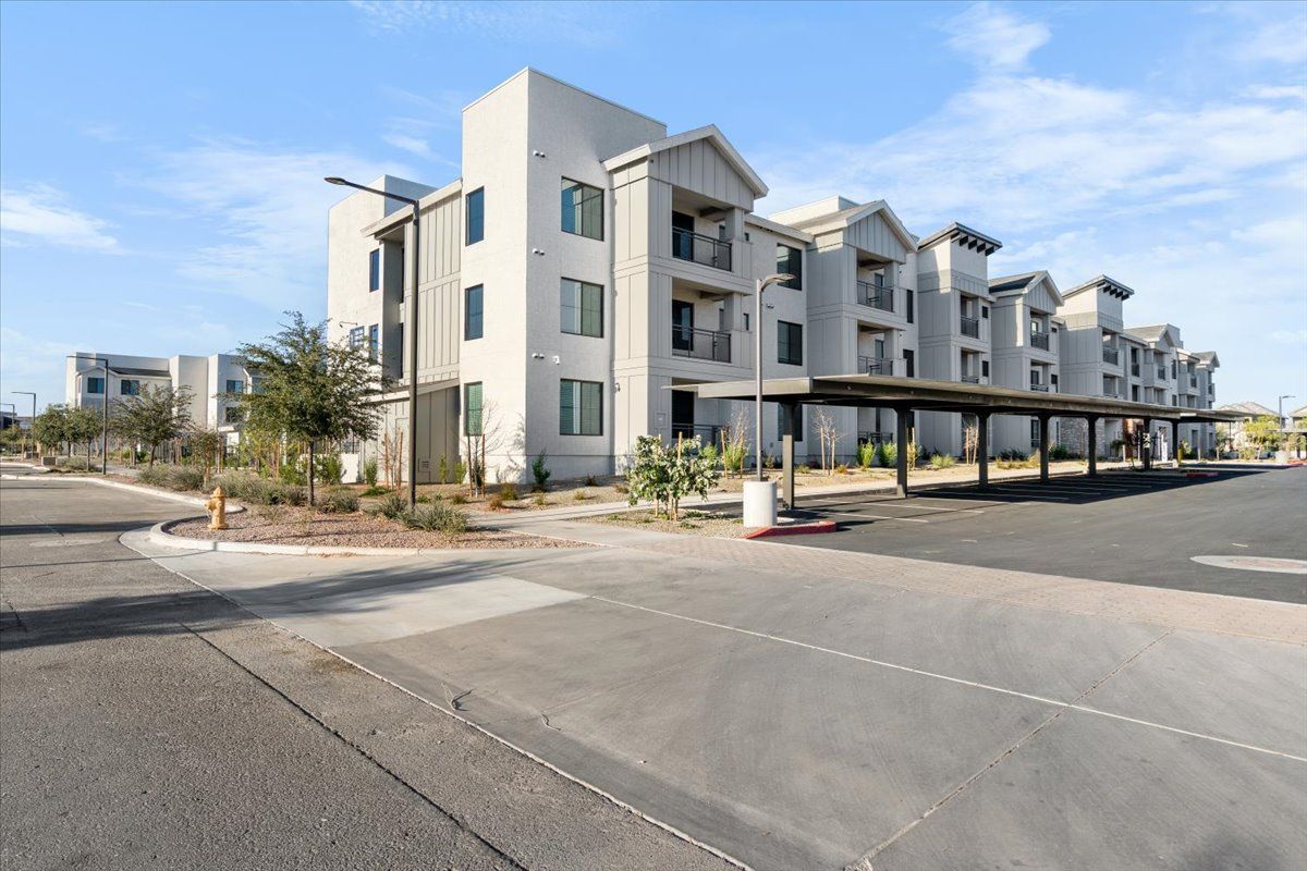 A large white apartment building with a parking lot in front of it.