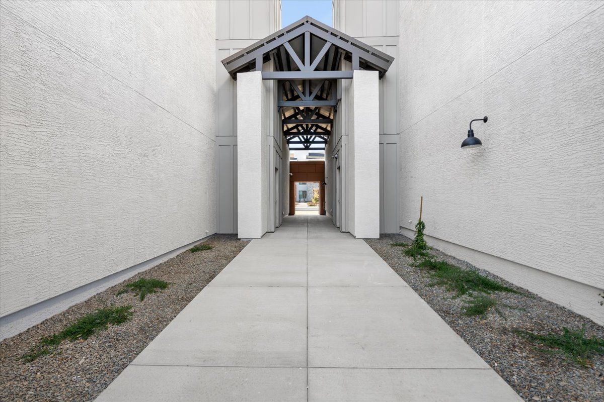 A narrow walkway between two buildings with a light on the wall