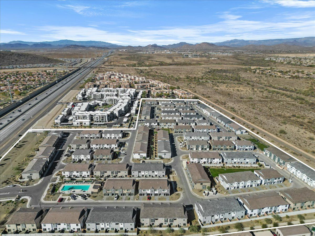 An aerial view of a residential area with a highway and mountains in the background.