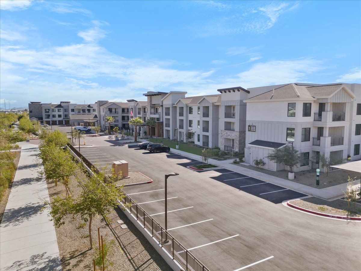 An aerial view of a large apartment building with a parking lot in front of it.