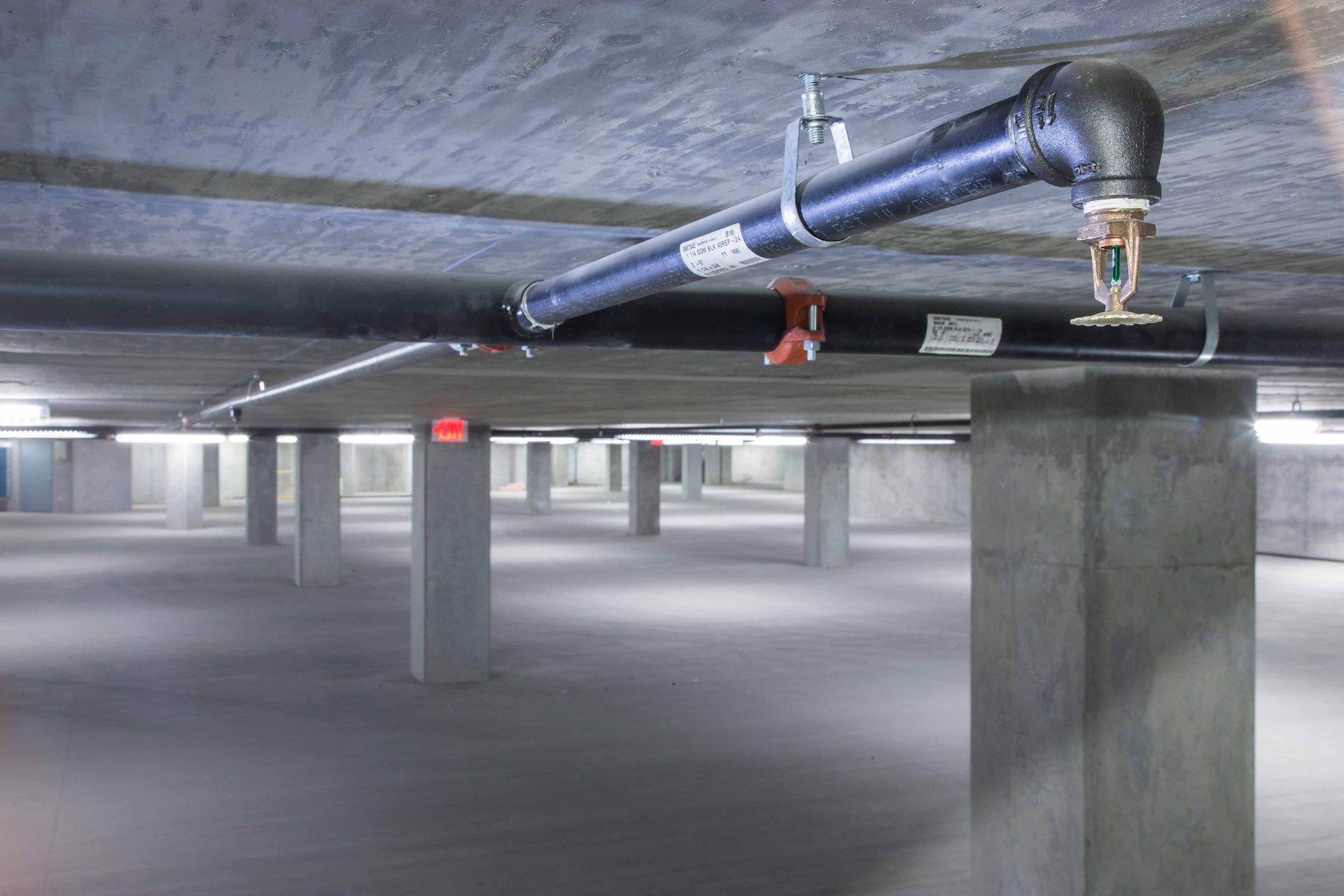 A sprinkler is hanging from the ceiling of a parking garage.