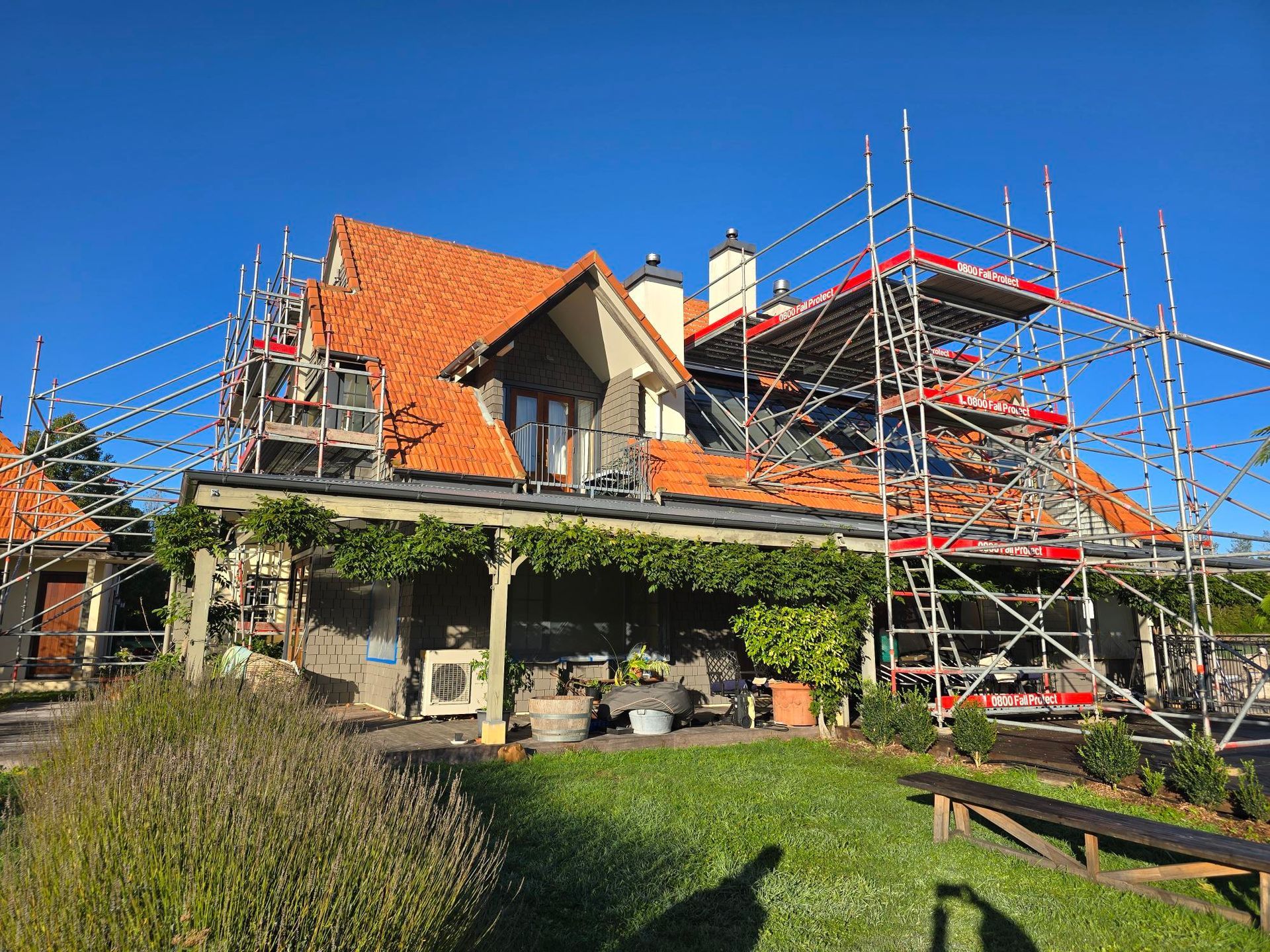 House with red tile roof and scaffolding, under construction on a sunny day.