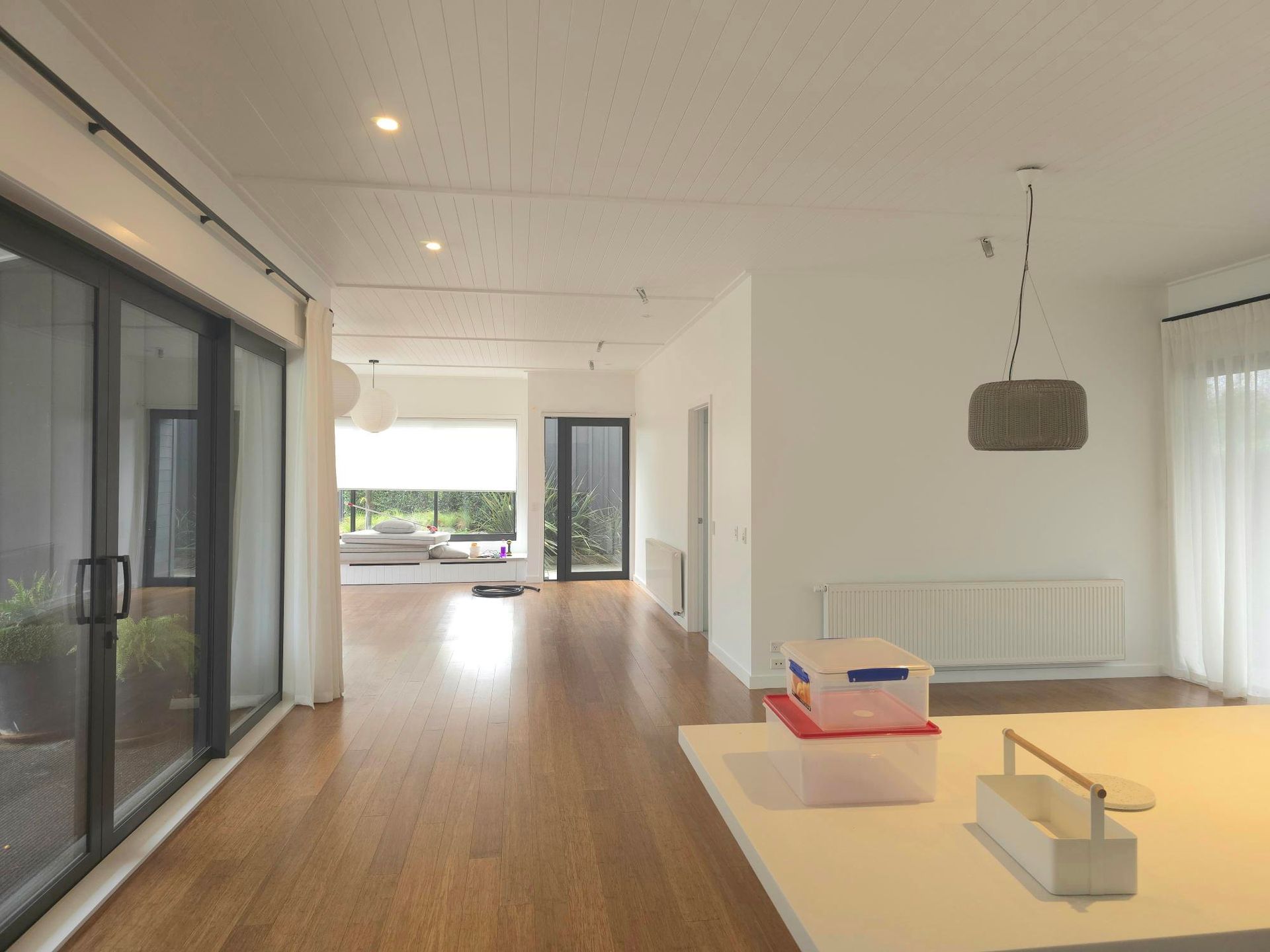 Bright modern living room with sliding glass doors, wooden floors, and white walls.