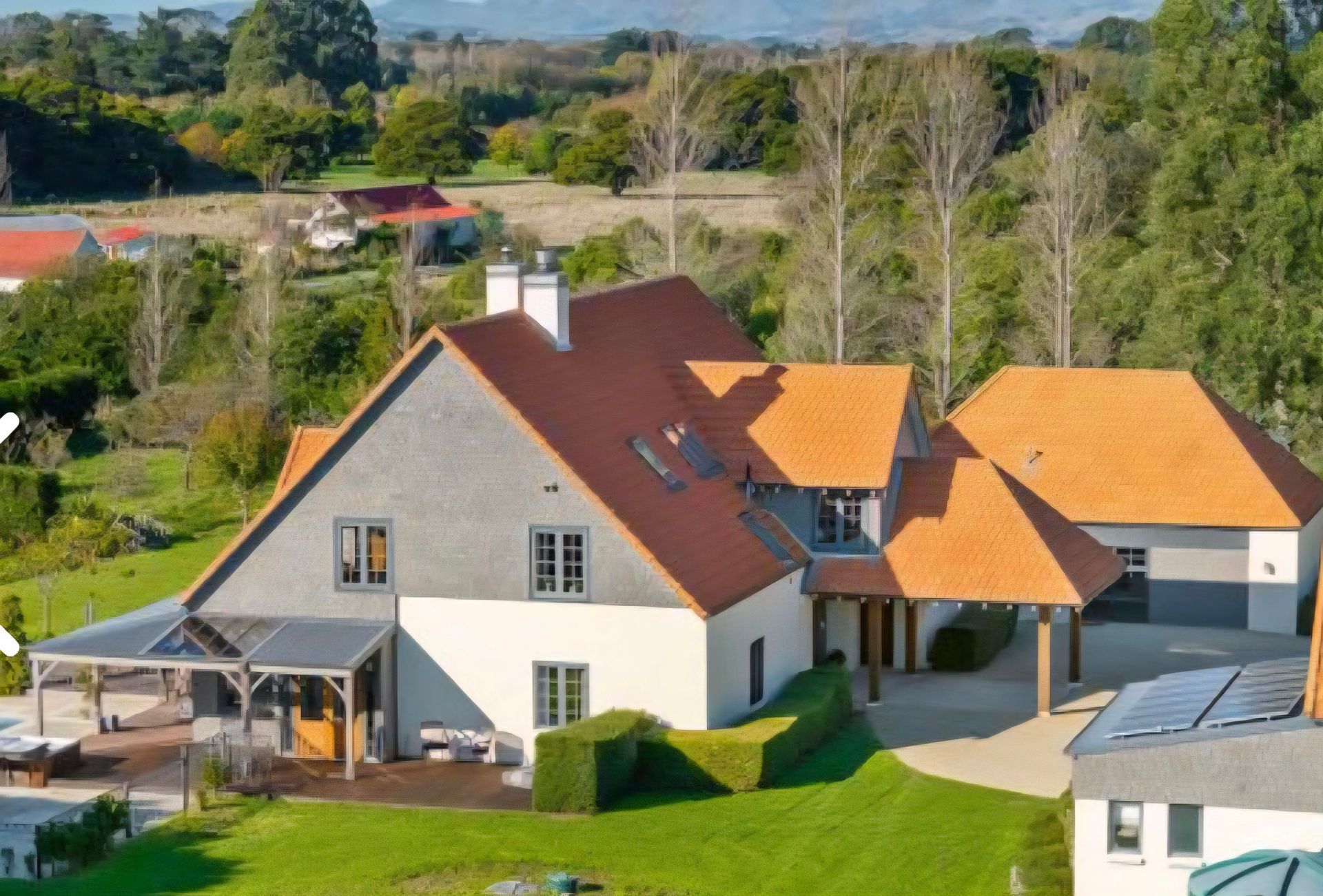 Person painting gray siding with a white paintbrush.
