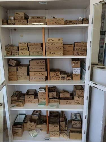 White cabinet filled with various brown boxes, shelves, and containers; a storage space.