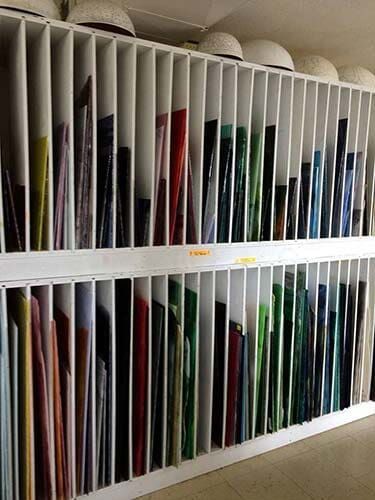 Shelves filled with various colored glass sheets in a workshop or store.