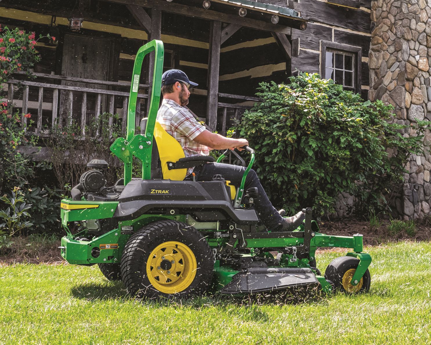 An olive-green riding lawn mower parked in a grassy field.
