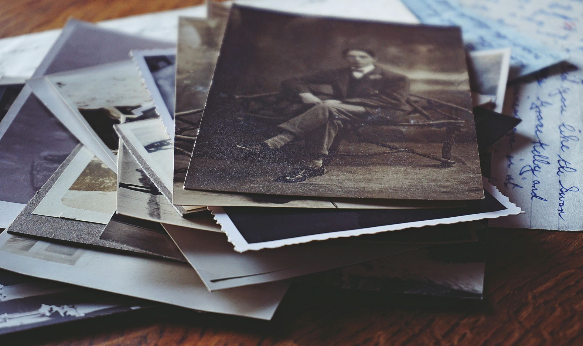Pile de photographies vintage, tons sépia, dont une d'un homme assis.