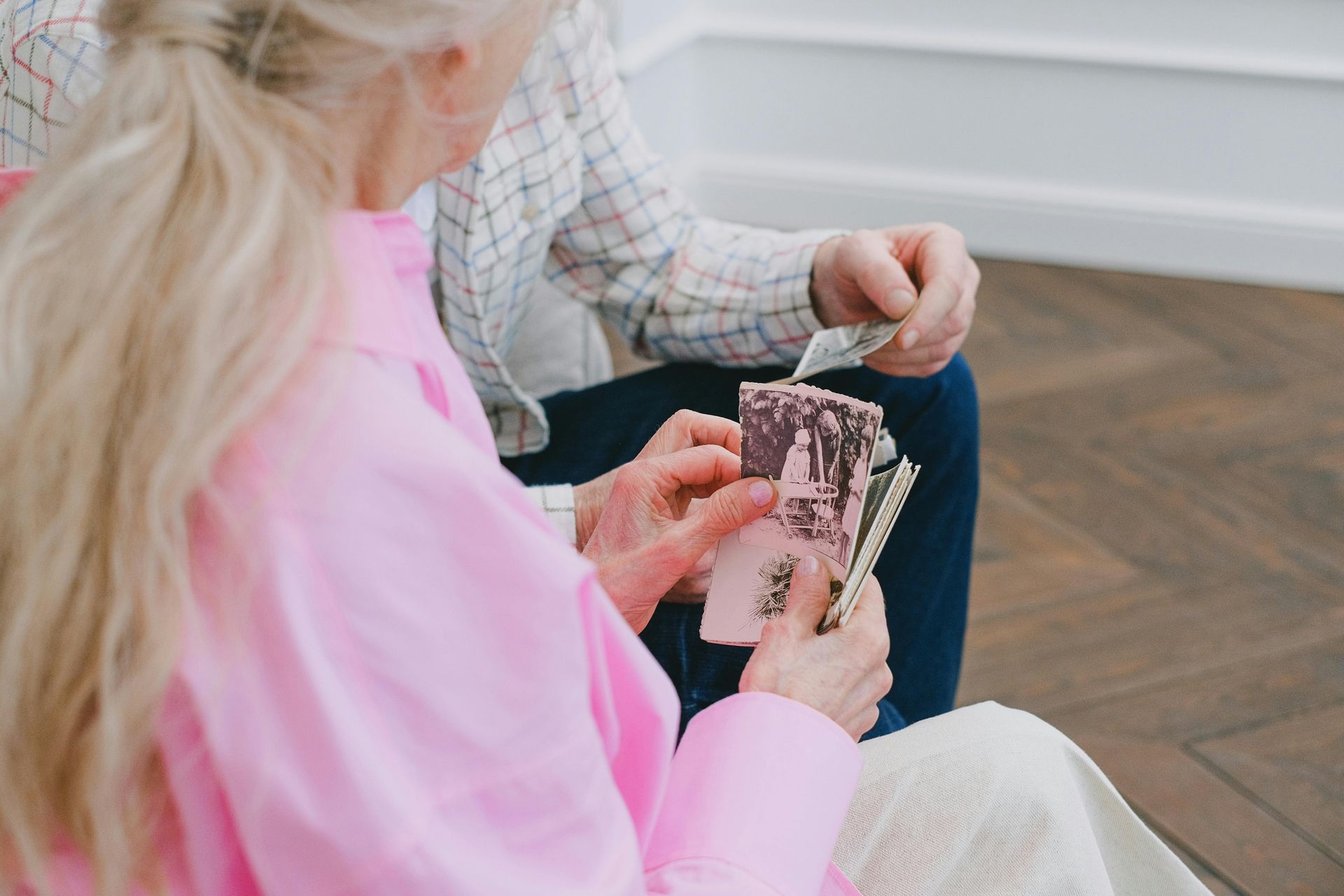 Tiiming vous accompagne dans votre planification successorale Un couple de personnes âgées, dont une femme en chemise rose, compte de l'argent. Un homme en arrière-plan lui tend de l'argent à l'intérieur.