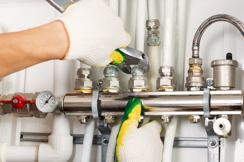 Plumbing Maintenance — Hand with Gloves by a Man Holding  Plumbing Tools in Plainfield, IN