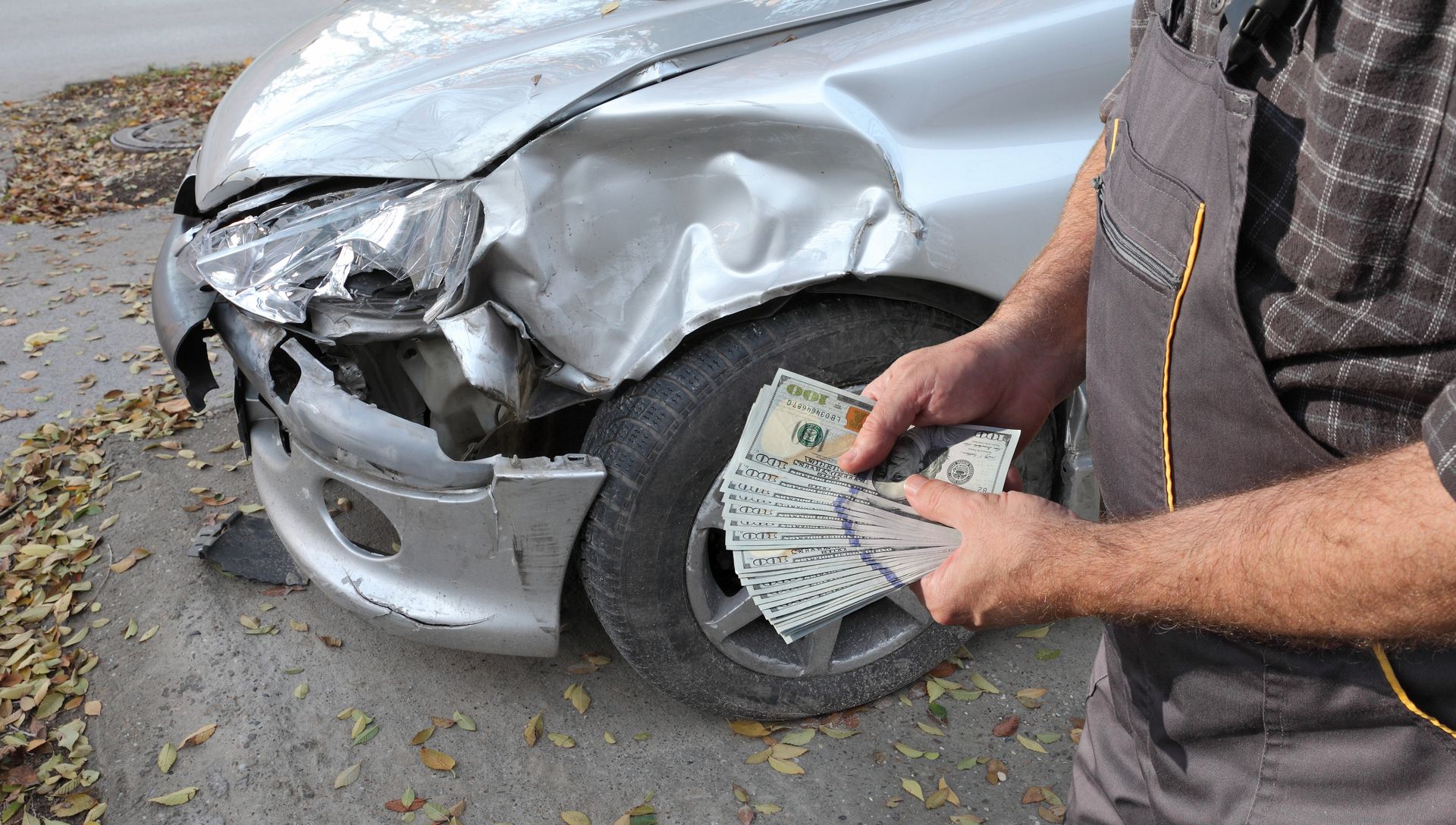 Junk car next to an unrecognized man with money on hands.