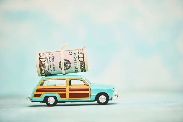 Toy vintage station wagon with cash roll on roof symbolizes quick cash for unwanted or junk vehicles.