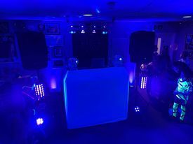 A dj booth is lit up with blue lights in a dark room.
