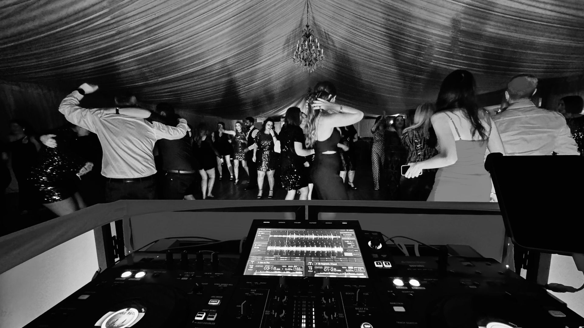 A black and white photo of a dj playing music at a party.