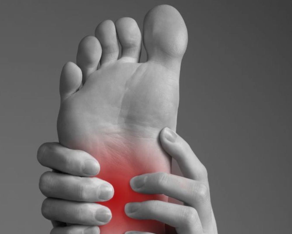 A black and white photo of a person holding their foot in pain