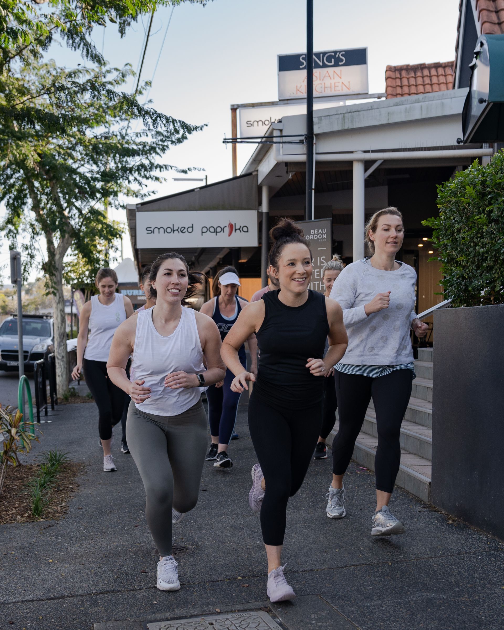 A group of women are running down a sidewalk.