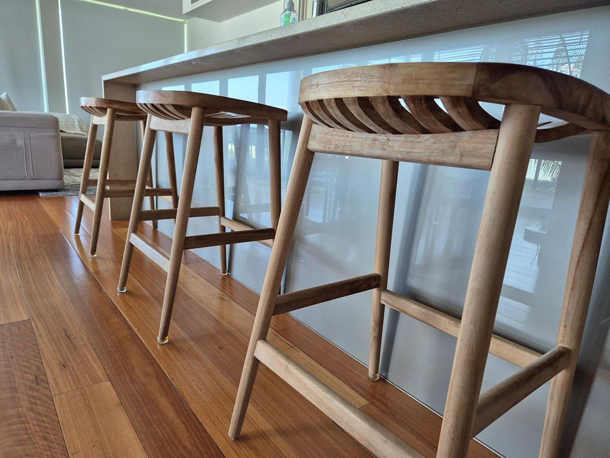 Three Wooden Bar Stools with Slatted Backs Sit at A Glossy White — KirraLina Cleaning Services in Tweed Heads, NSW