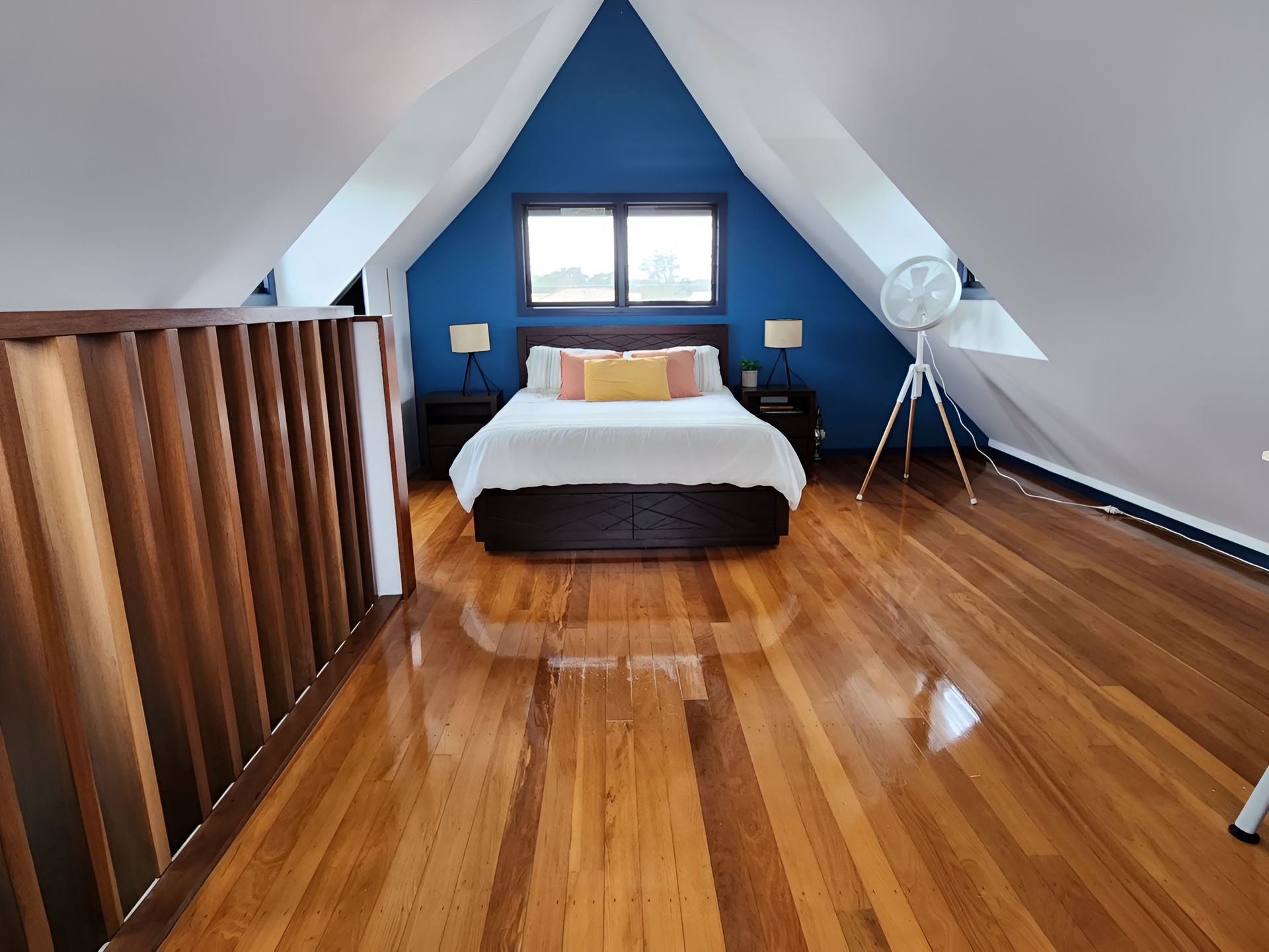 A light-filled bedroom with a large arch mirror reflecting a bed, plant, and sitting area with a beige chair — KirraLina Cleaning Services in Tweed Heads, NSW