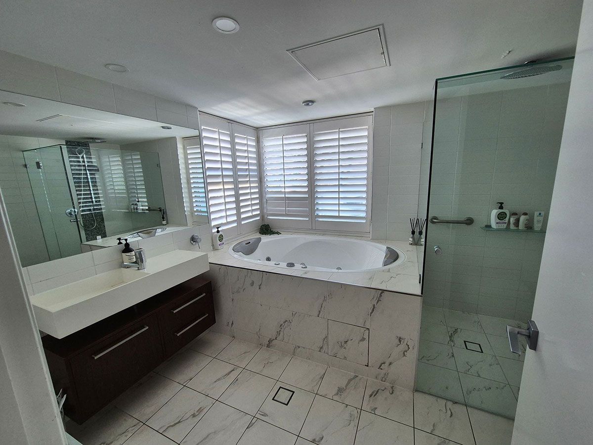 A Modern Bathroom with A White Bathtub, Shower, Vanity, and Large Mirror — KirraLina Cleaning Services in Tweed Heads, NSW
