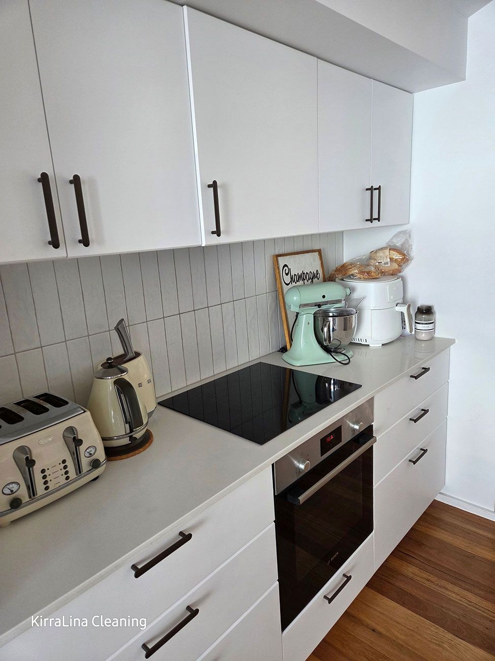 White Kitchen with Black Appliances and Handles — KirraLina Cleaning Services in Tweed Heads, NSW