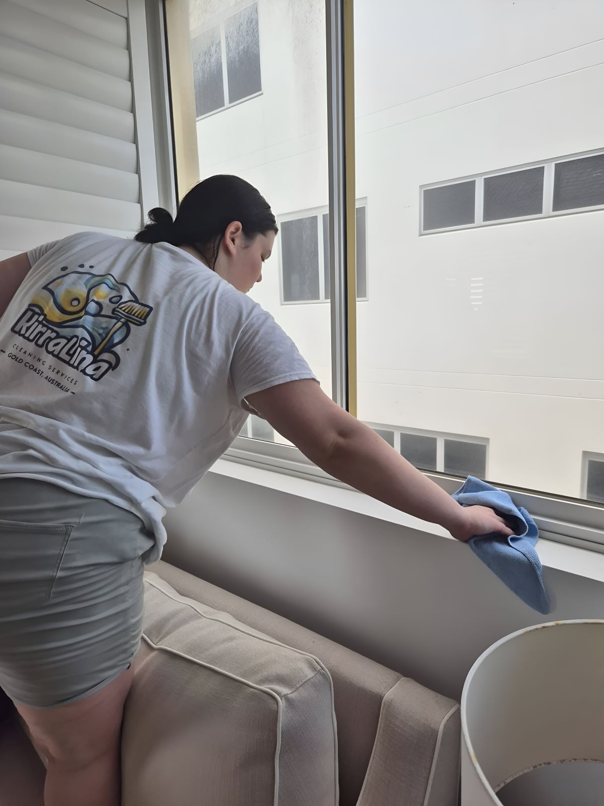 A Woman Is Cleaning a Window — KirraLina Cleaning Services in Tweed Heads, NSW
