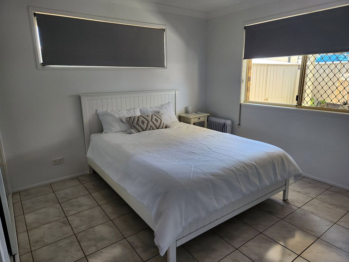 White Bedroom with Bed, Two Windows with Blinds, and Tiled Floor — KirraLina Cleaning Services in Tweed Heads, NSW