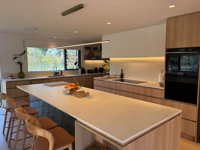 Modern Kitchen with Light Wood Cabinets, White Countertops, and A Large Island with Seating — KirraLina Cleaning Services in Tweed Heads, NSW