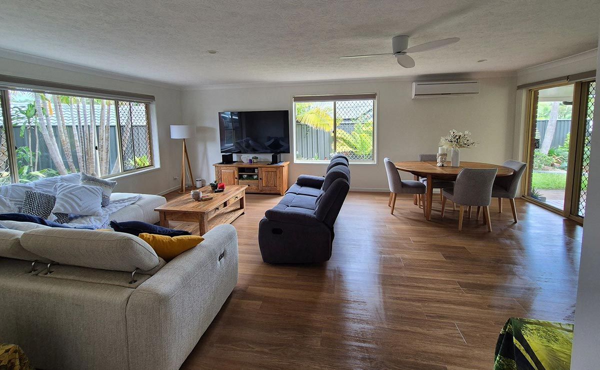 Spacious Living Room with Hardwood Floors, a Large Sofa, Tv, Dining Table — KirraLina Cleaning Services in Tweed Heads, NSW