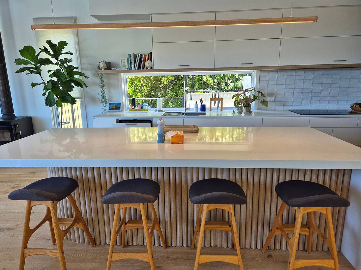 Modern Kitchen with White Countertops, Wooden Island, and Stools — KirraLina Cleaning Services in Tweed Heads, NSW