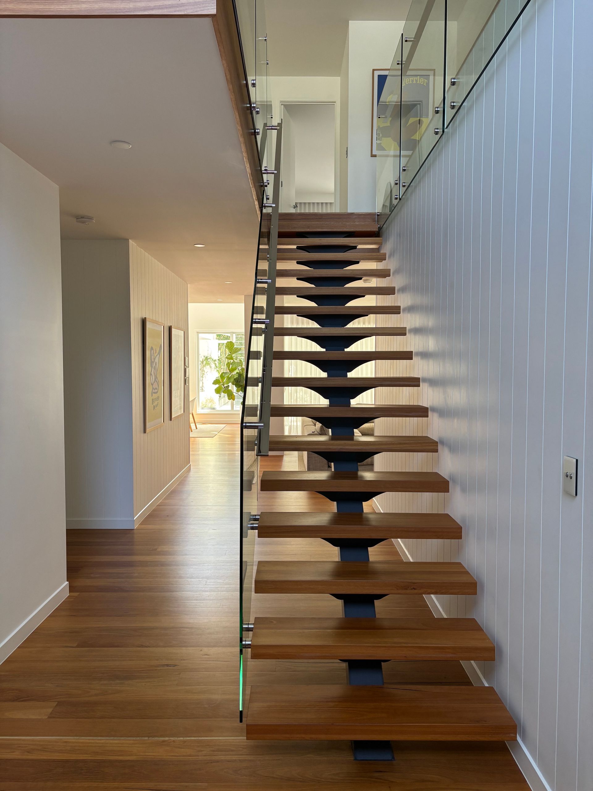 Wooden staircase with glass railing. Sunlight creates speckled patterns on a white wall — KirraLina Cleaning Services in Tweed Heads, NSW