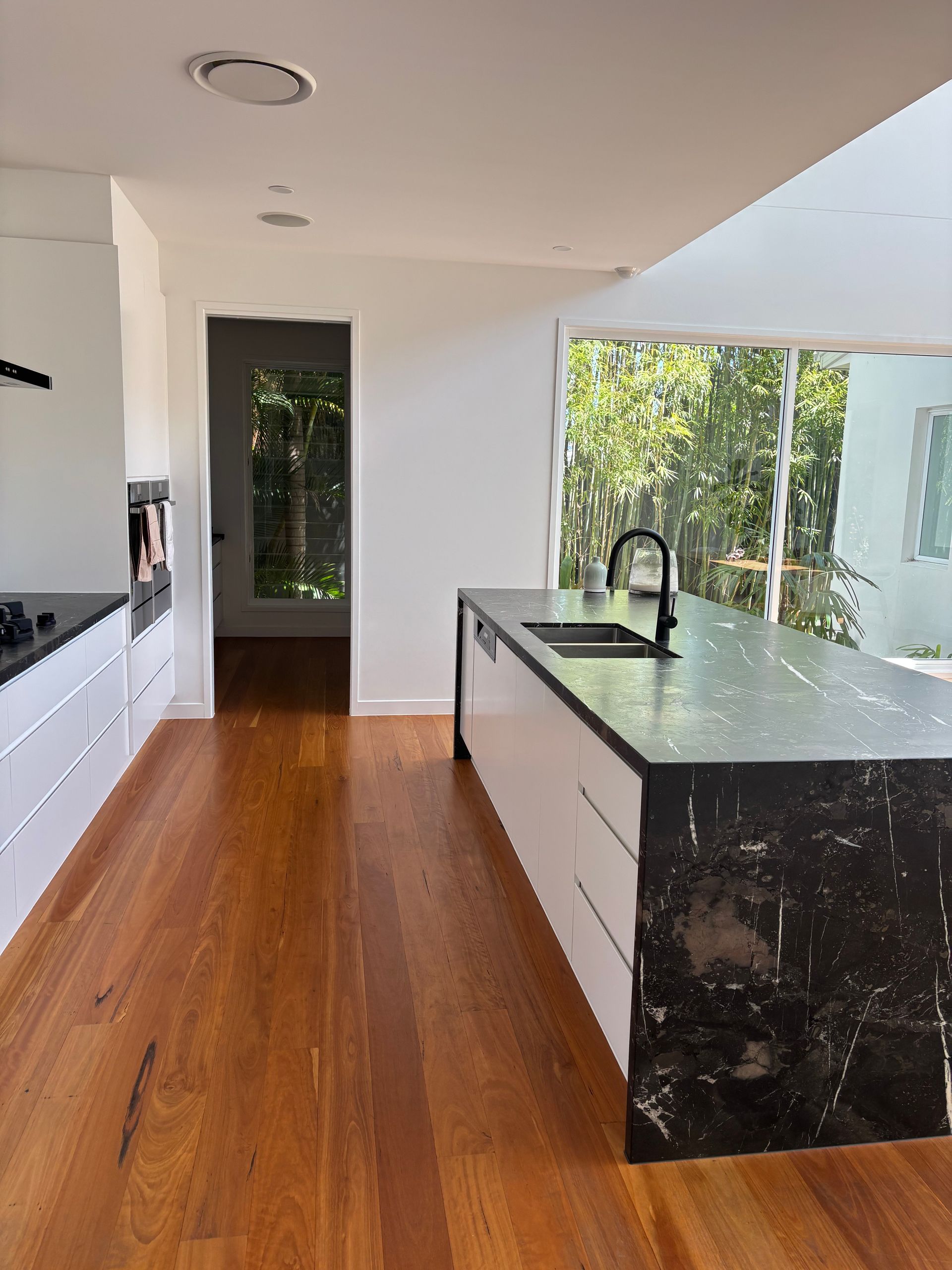 Modern kitchen with wood floors, white cabinets, and a black countertop island — KirraLina Cleaning Services in Tweed Heads, NSW