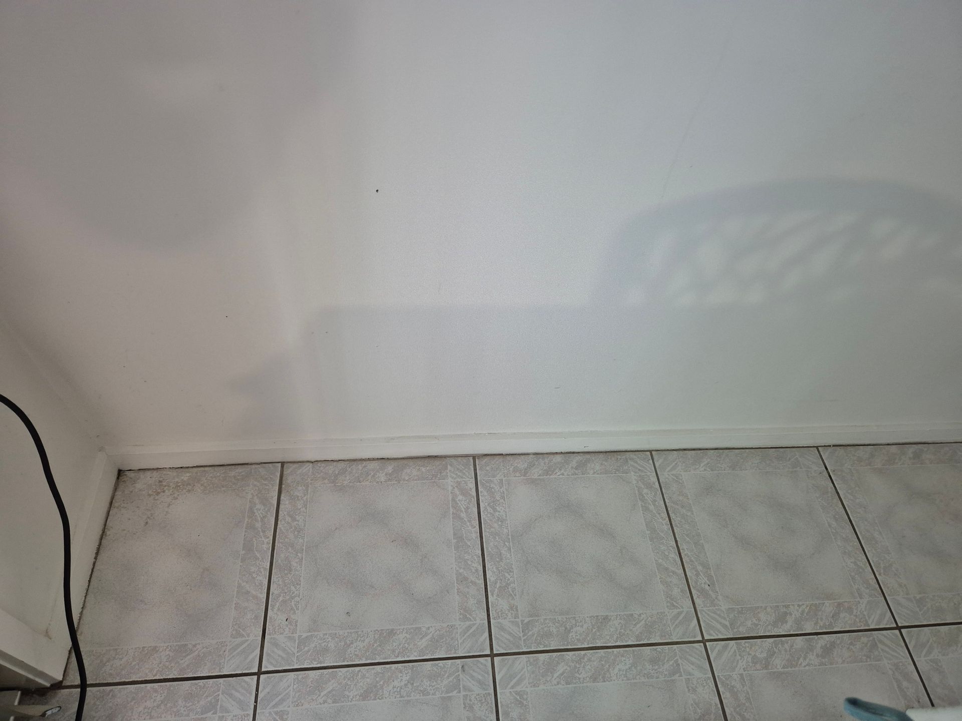 After: White Wall Meeting Grey Tiled Floor. A Black Cable Runs Down the Wall — KirraLina Cleaning Services in Banora Point, NSW