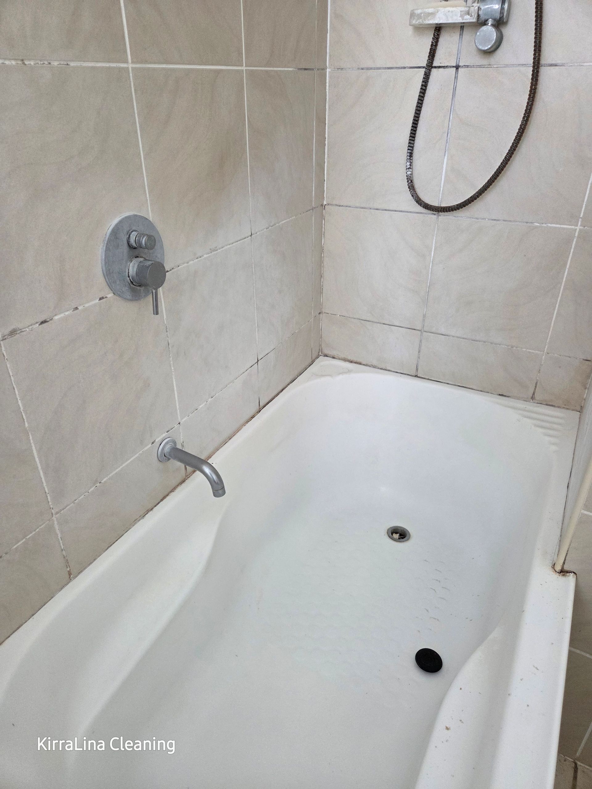 Bathtub with white enclosure and faucet, set in a tiled bathroom. Silver controls on the wall — KirraLina Cleaning Services in Tweed Heads, NSW
