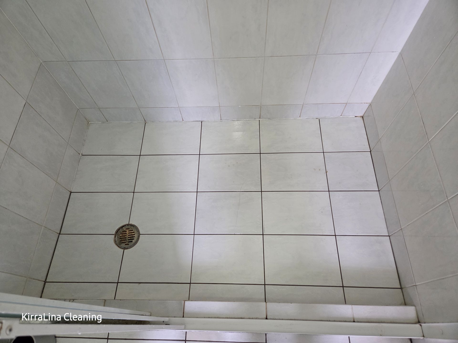 White tiled shower stall with a drain and step-up threshold, viewed from above. — KirraLina Cleaning Services in Tweed Heads, NSW