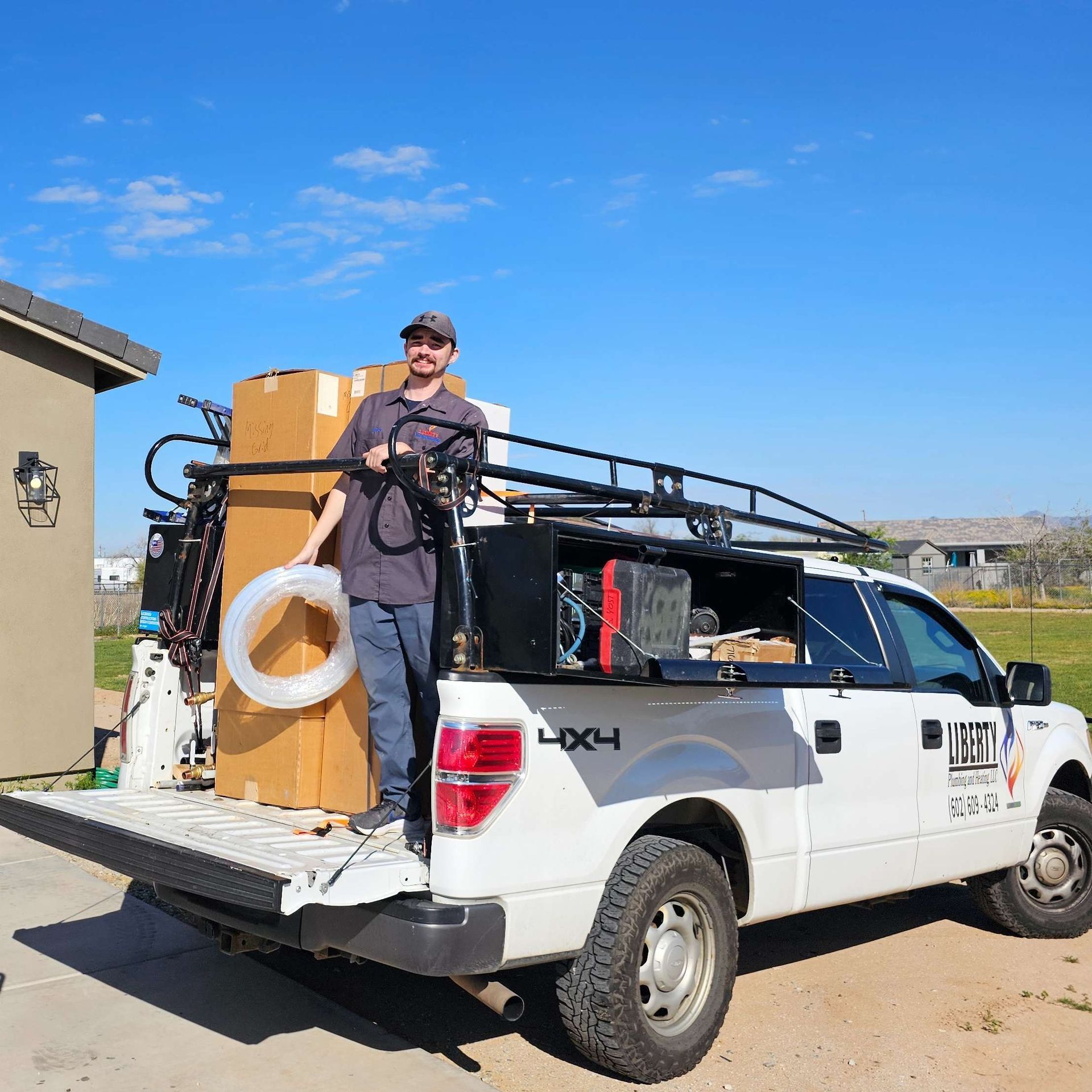 Man standing near a white pickup truck loaded with equipment under a clear, blue sky.
