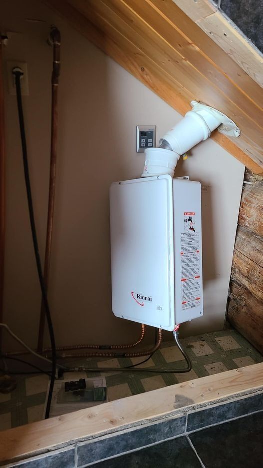 White water heater with vent pipe installed in a small, angled alcove. Copper pipes and electrical wires visible.