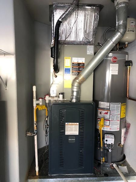 Furnace and water heater in a utility closet, with vent pipes.