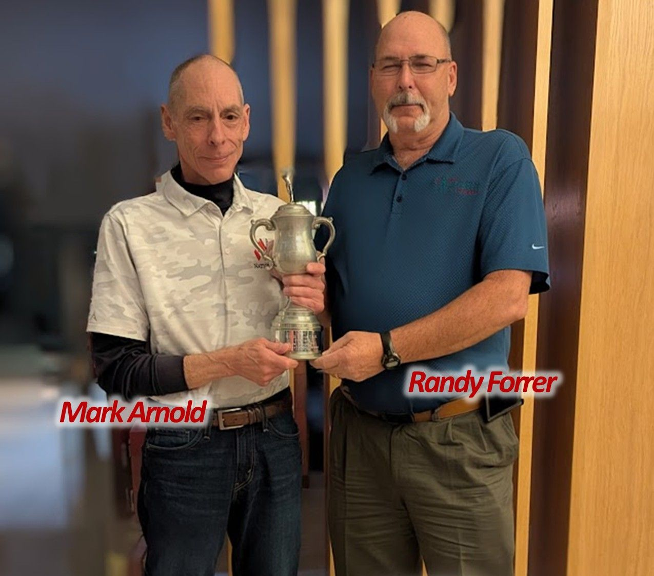 Two men holding a silver trophy. Mark Arnold and Randy Forrer stand side-by-side