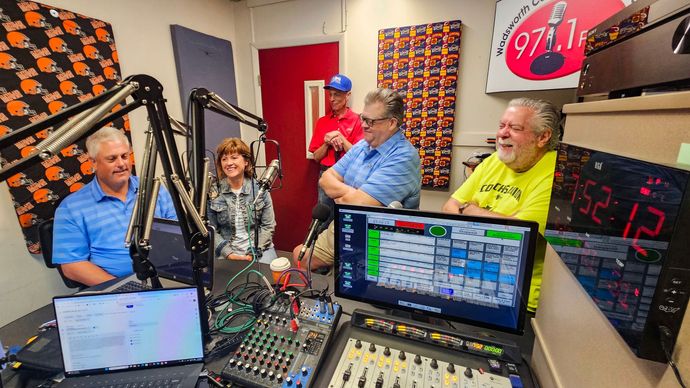 A group of 4 men are sitting at a table being interviewed at the 97.1 fm radio station.