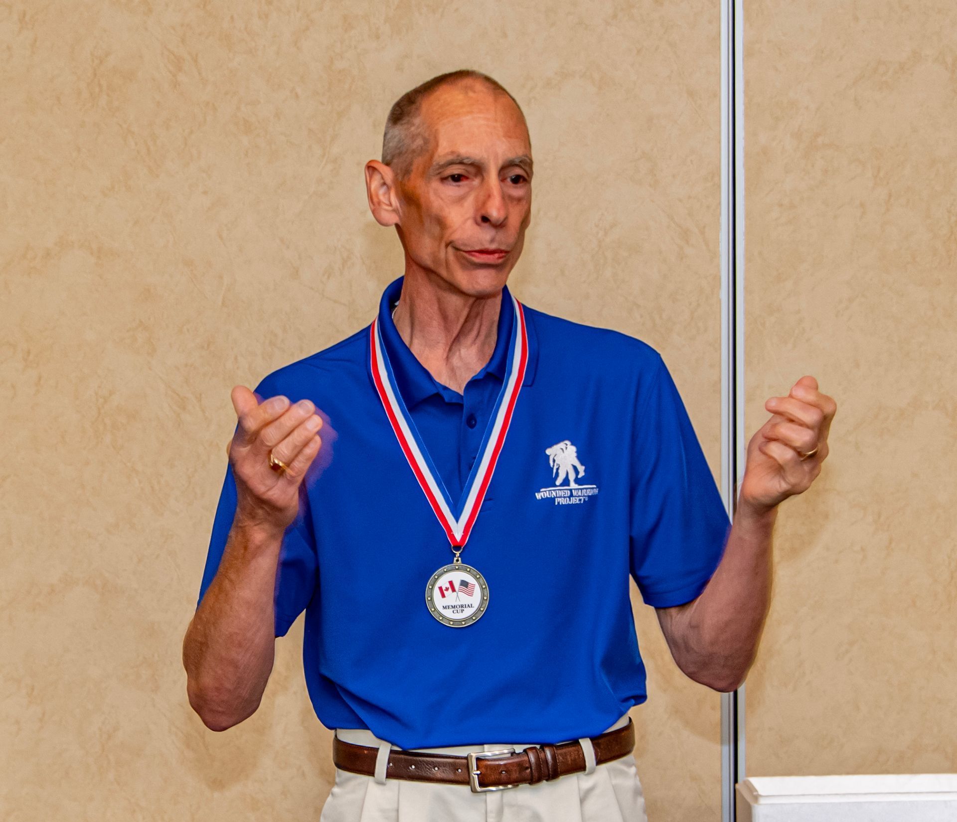 A man in a blue shirt is wearing a medal around his neck