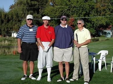 Four men are posing for a picture on a golf course