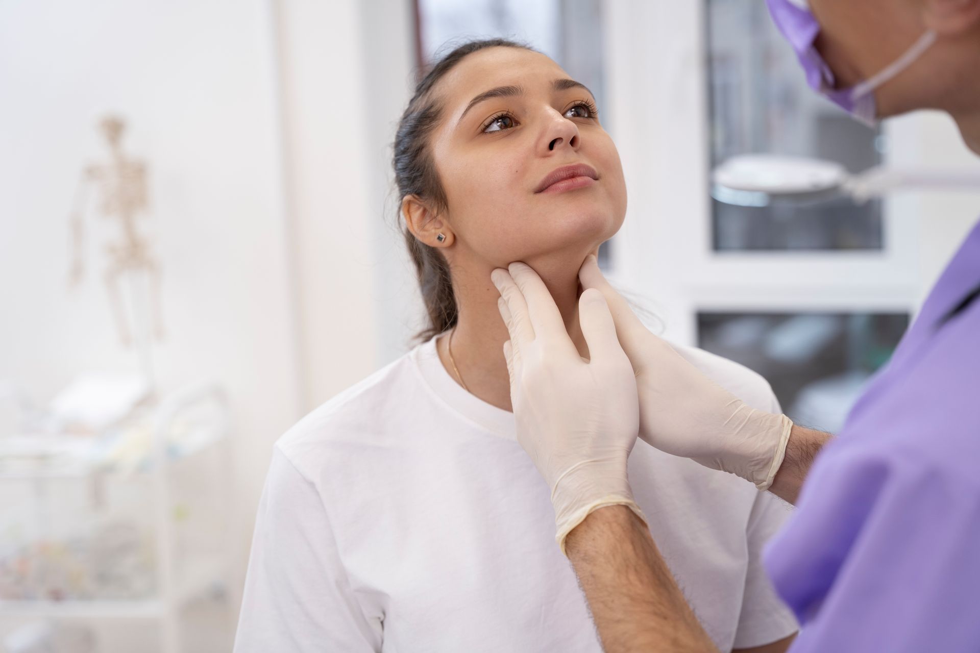 Doctor examining a patient's neck in a medical office.