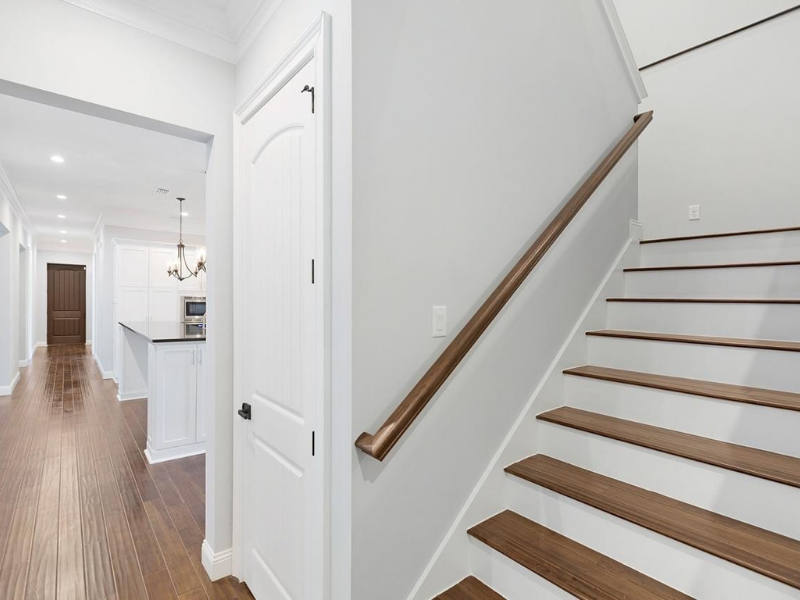 Interior view: hallway with wooden floors, stairs with wood treads, and white walls.