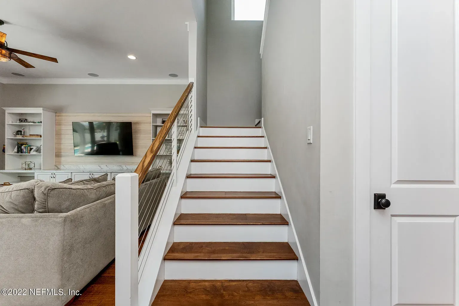 Empty room with dark hardwood floors, two chandeliers, and a window.
