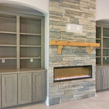 Stone fireplace with wooden mantle and electric fire; built-in bookshelves on each side.