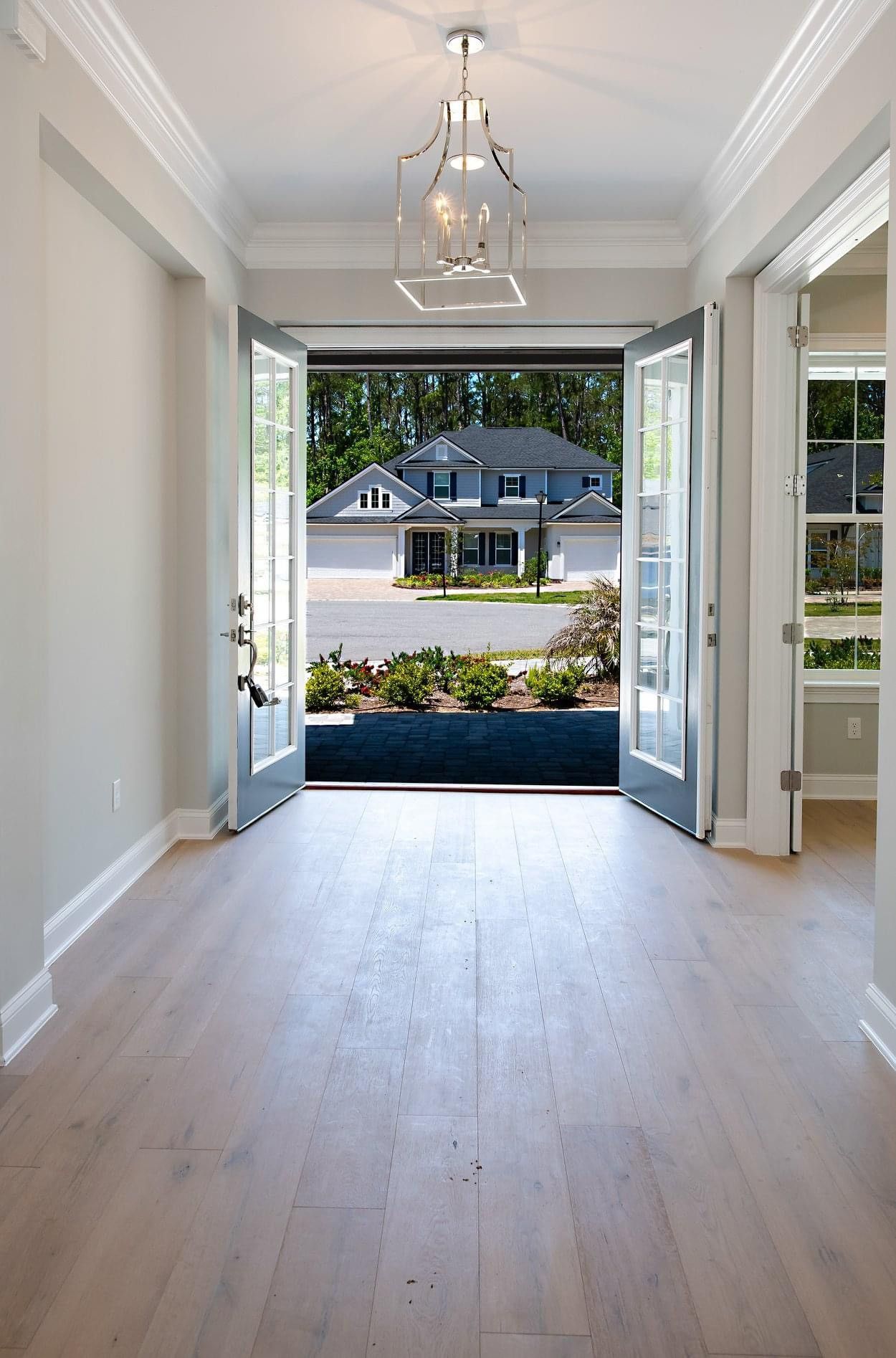 Entryway with open French doors revealing a view of a house across the street.