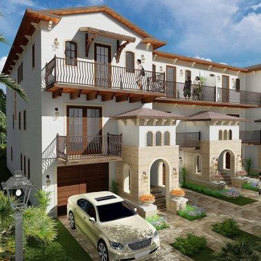 Luxury townhomes with balconies, stone arches, and a car in the driveway, exterior view.