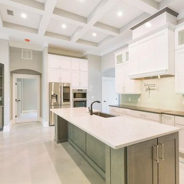 Modern kitchen with white cabinets, gray island, and coffered ceiling.